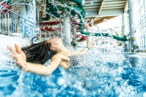 Une personne nage dans une piscine, et l’eau éclabousse autour d’elle.