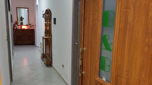 Un pasillo con una puerta de madera que tiene un letrero verde y blanco, un espejo y un mueble de madera.