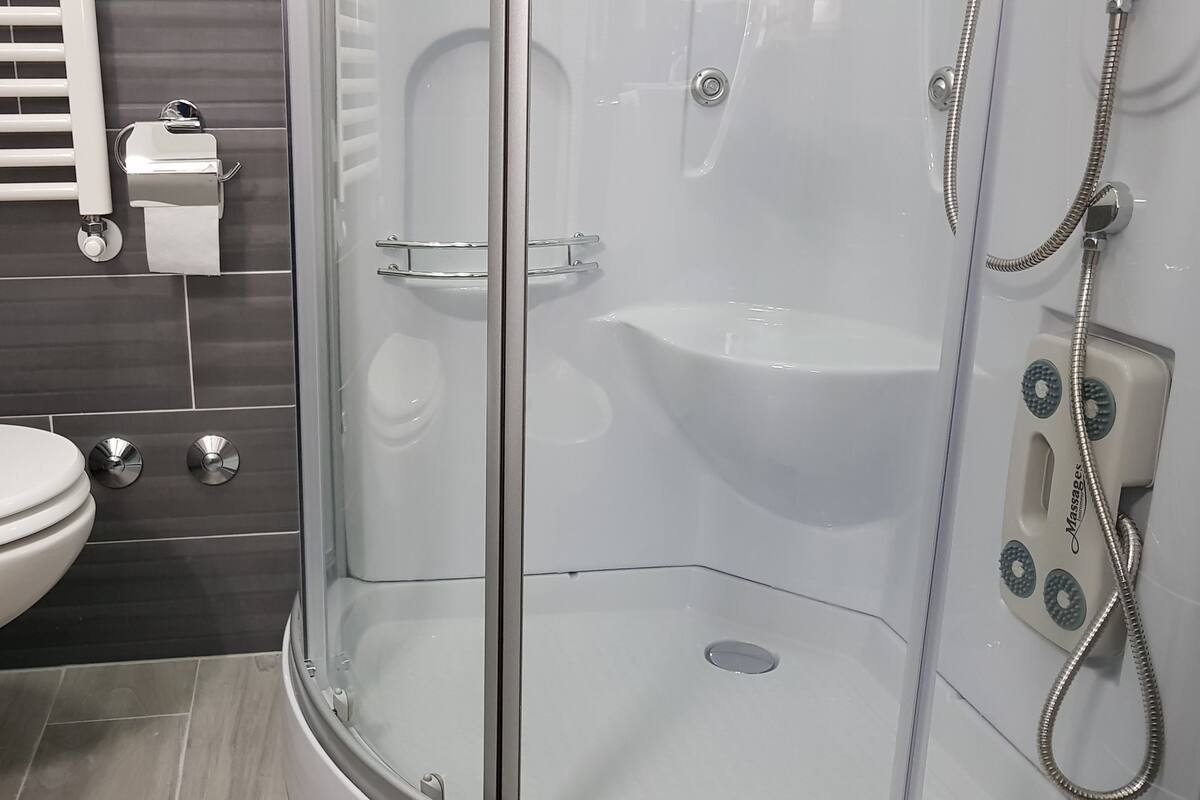 A modern bathroom with a toilet, a glass-enclosed shower, and a towel rack.