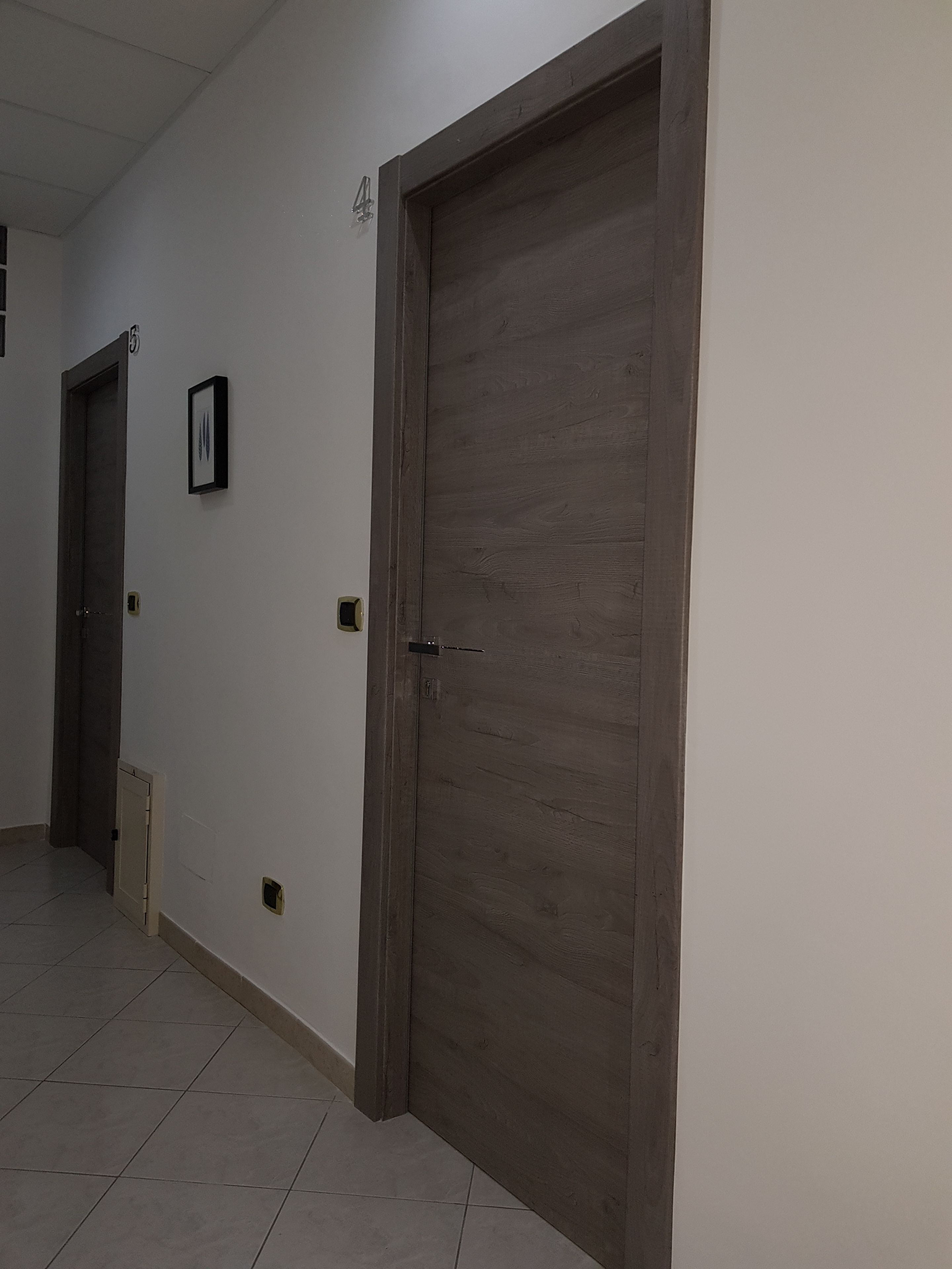 A hallway with two wooden doors, one with a number '5' above it, and a small framed picture on the wall.