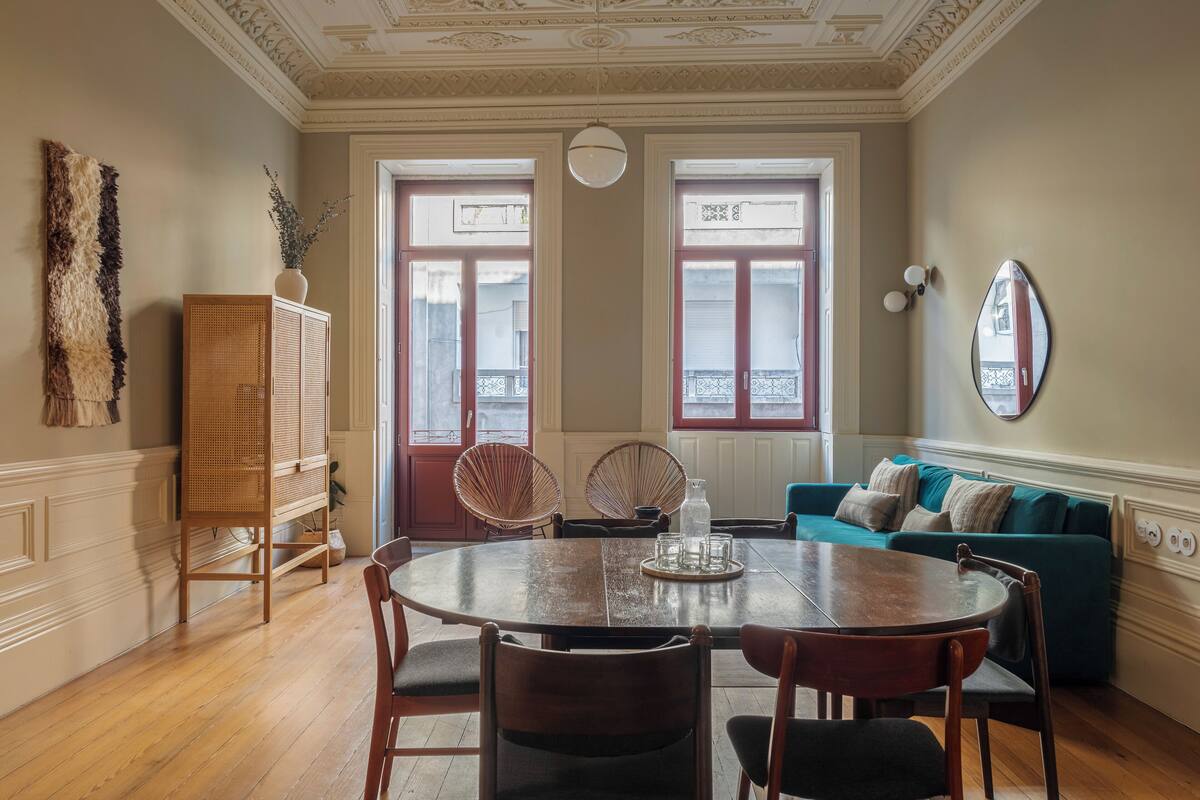 A dining area with a round table, chairs, a cabinet, and a sofa.