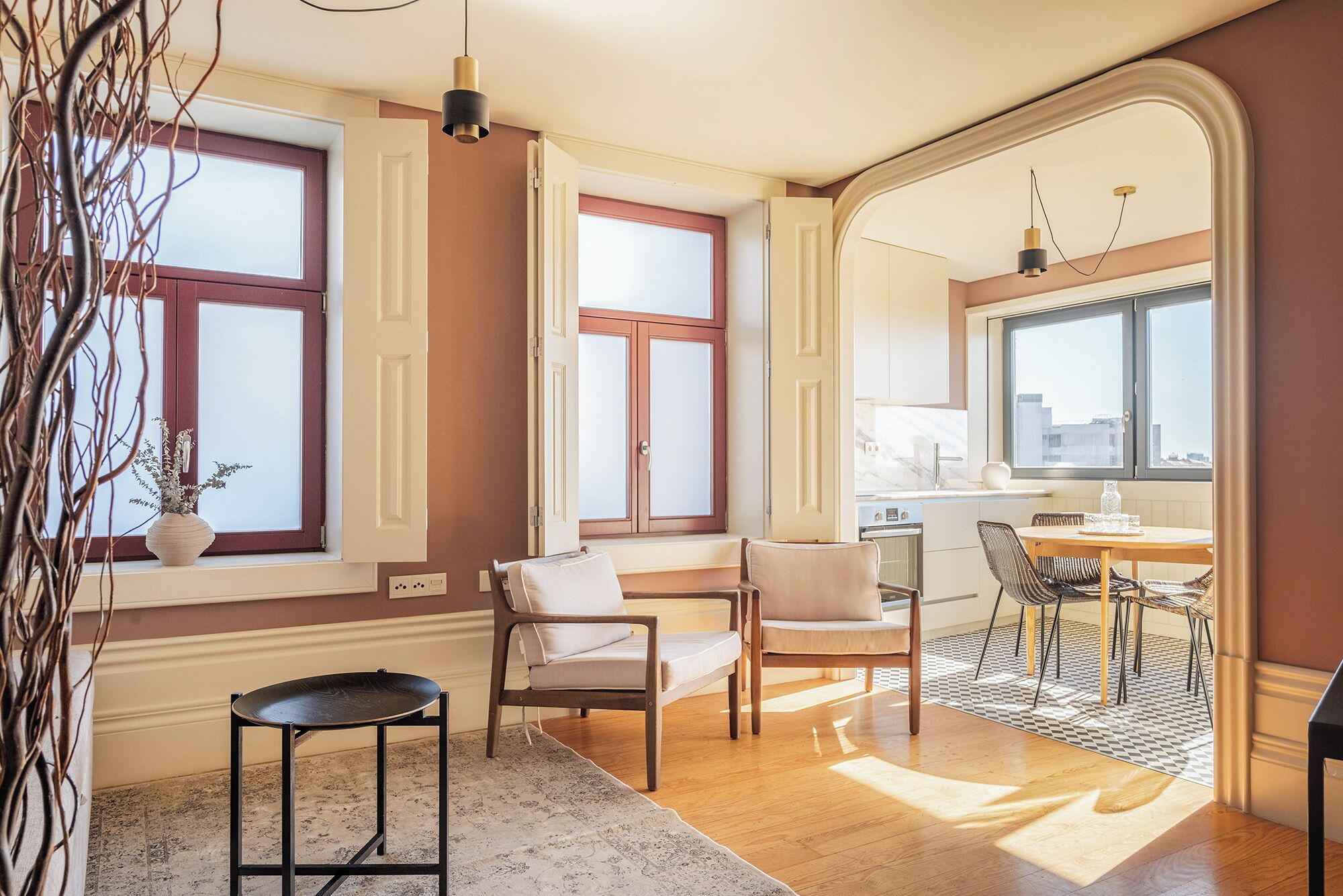 A modern kitchen with a dining area, wooden flooring, and a view of the city.