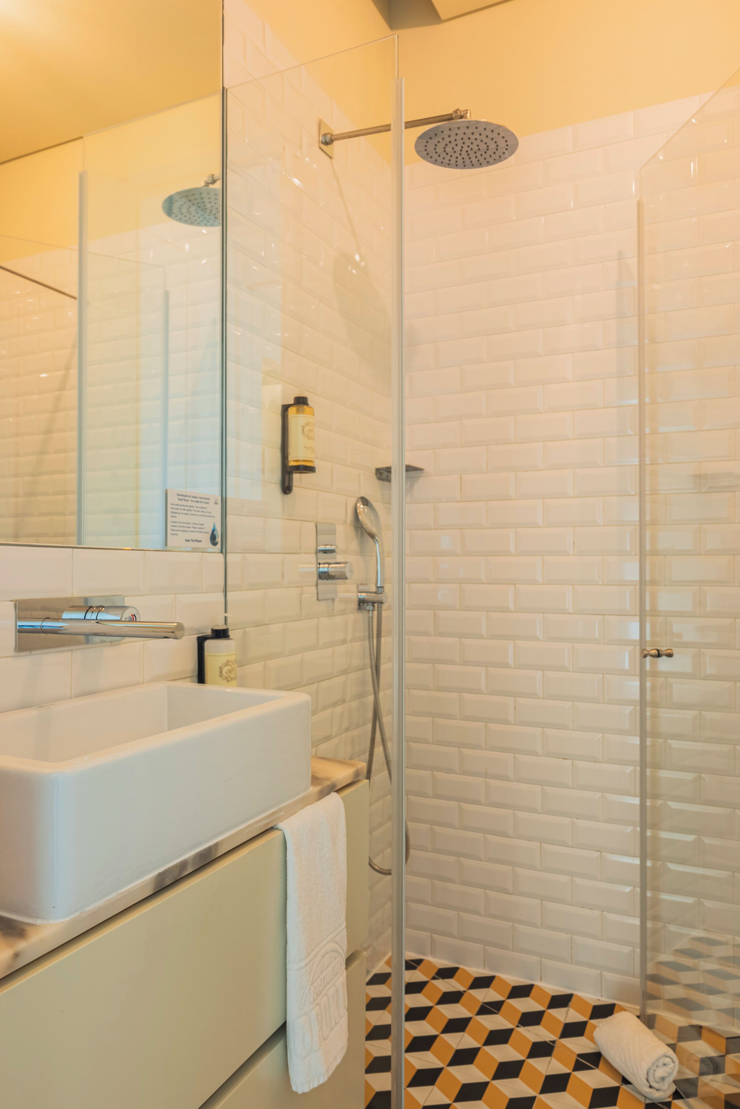 A modern bathroom with a glass-enclosed shower, a white sink, and a tiled floor.