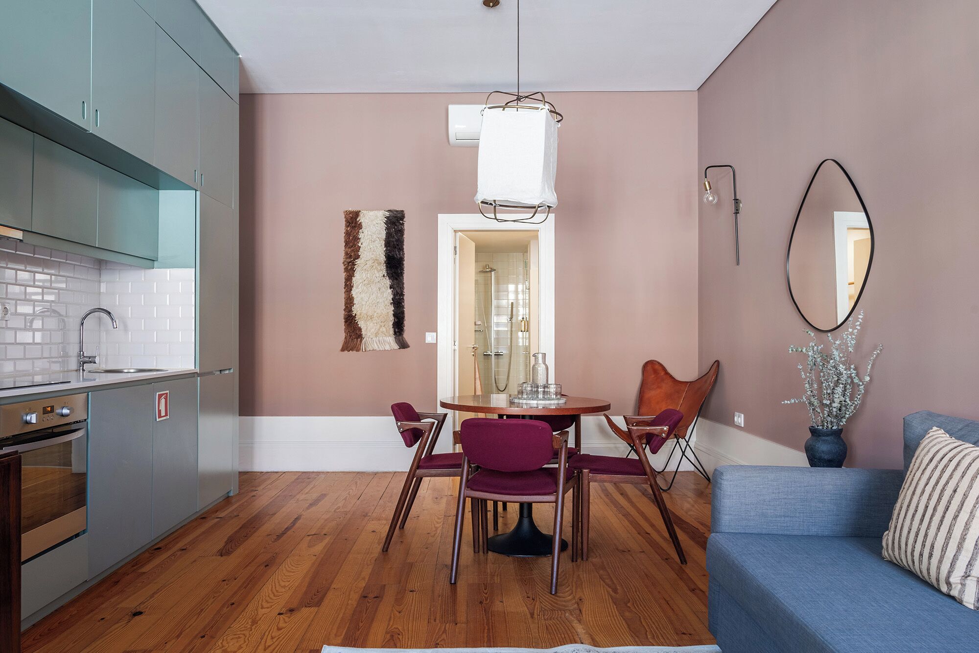 A modern kitchen with a built-in oven and a dining area with a round table and chairs.