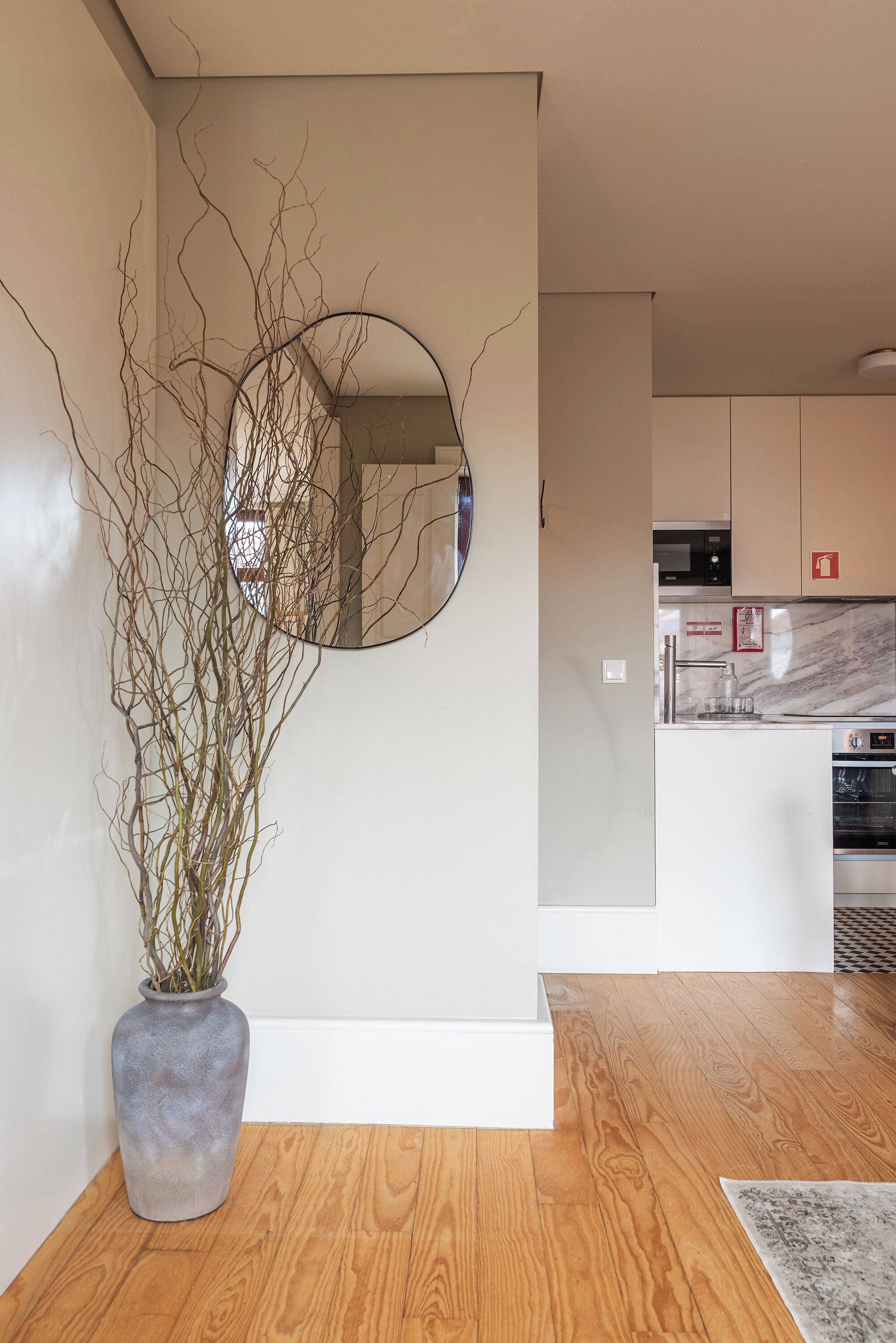 A modern kitchen with white cabinets, a marble countertop, and a built-in oven.