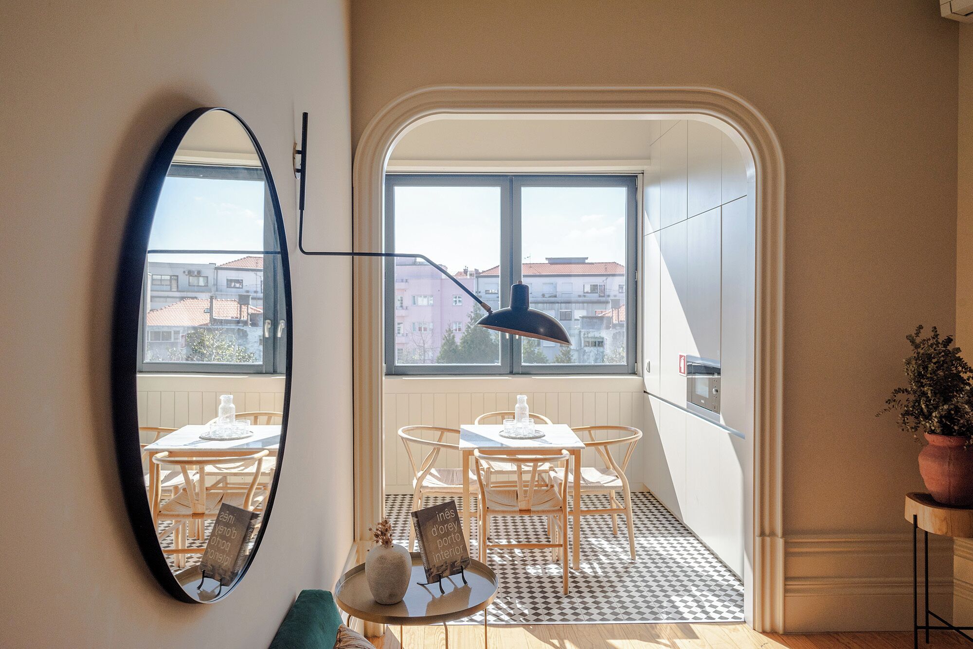 Ein kompakter Wohnbereich mit Essplatz, einem großen Spiegel und Blick auf die Stadt durch ein Fenster.