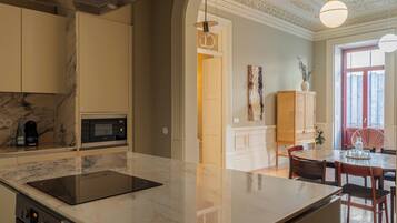 A modern kitchen with a marble countertop, built-in appliances, and a dining area with a wooden table and chairs.