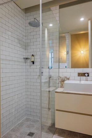 A modern bathroom with white tiled walls, a glass shower enclosure, a white bathtub, and a vanity with a mirror. - Oporto Maison Alves da Veiga (Porto)