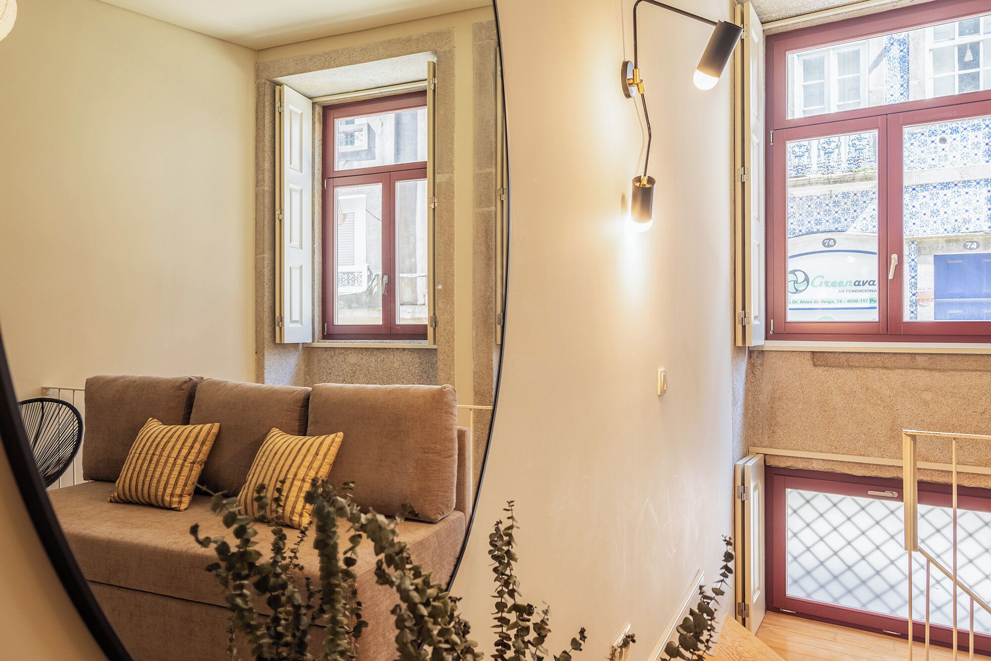 A cozy living room with a sofa, a window with a view, and a plant.