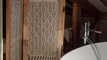 A bathroom with a large bathtub, wooden beams, and a checkered floor.