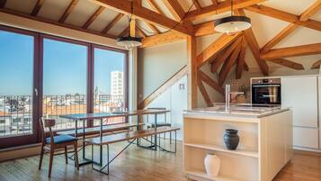 A modern kitchen with wooden beams, a large window, and a view of the city.