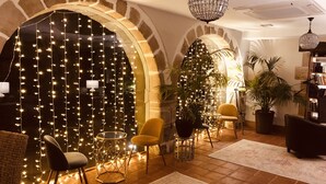 An interior with arched brick walls, string lights, a chandelier, and furniture including chairs and a bookshelf. - Hotel Palacio de Arce (Pielagos)