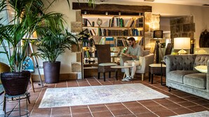 A cozy living room with a fireplace, a bookshelf, and a large potted plant. - Hotel Palacio de Arce (Pielagos)