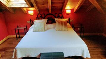 A room with a bed, two bedside tables, a bench, and a skylight.