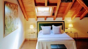 A bedroom with a sloped ceiling, a bed, bedside lamps, and a skylight. - Hotel Palacio de Arce (Pielagos)