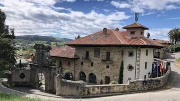 Un edificio de piedra con techo de tejas, un letrero que indica restaurante y vistas del paisaje circundante.