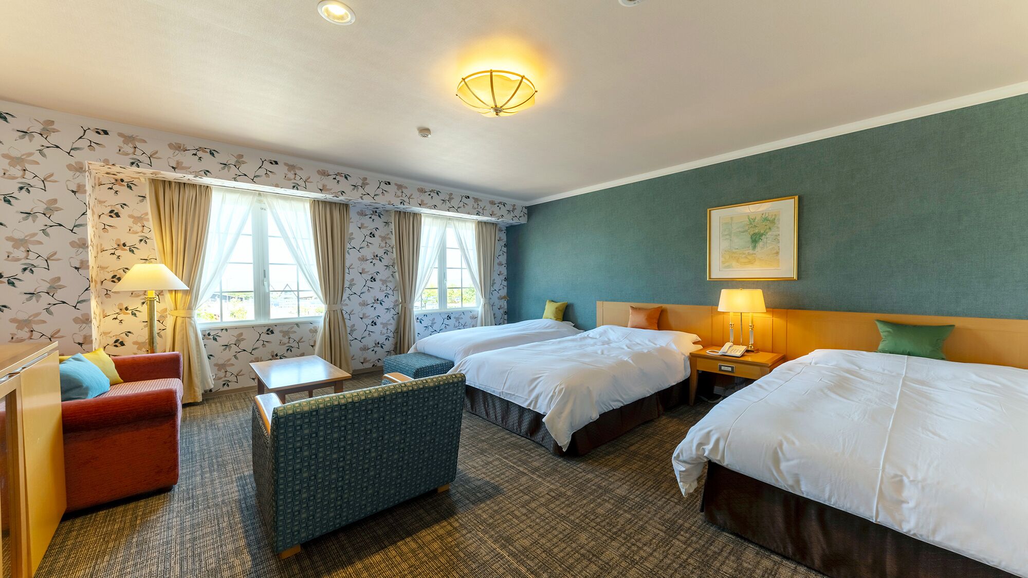 A hotel room with two beds, a sofa, a small table, and a chair.