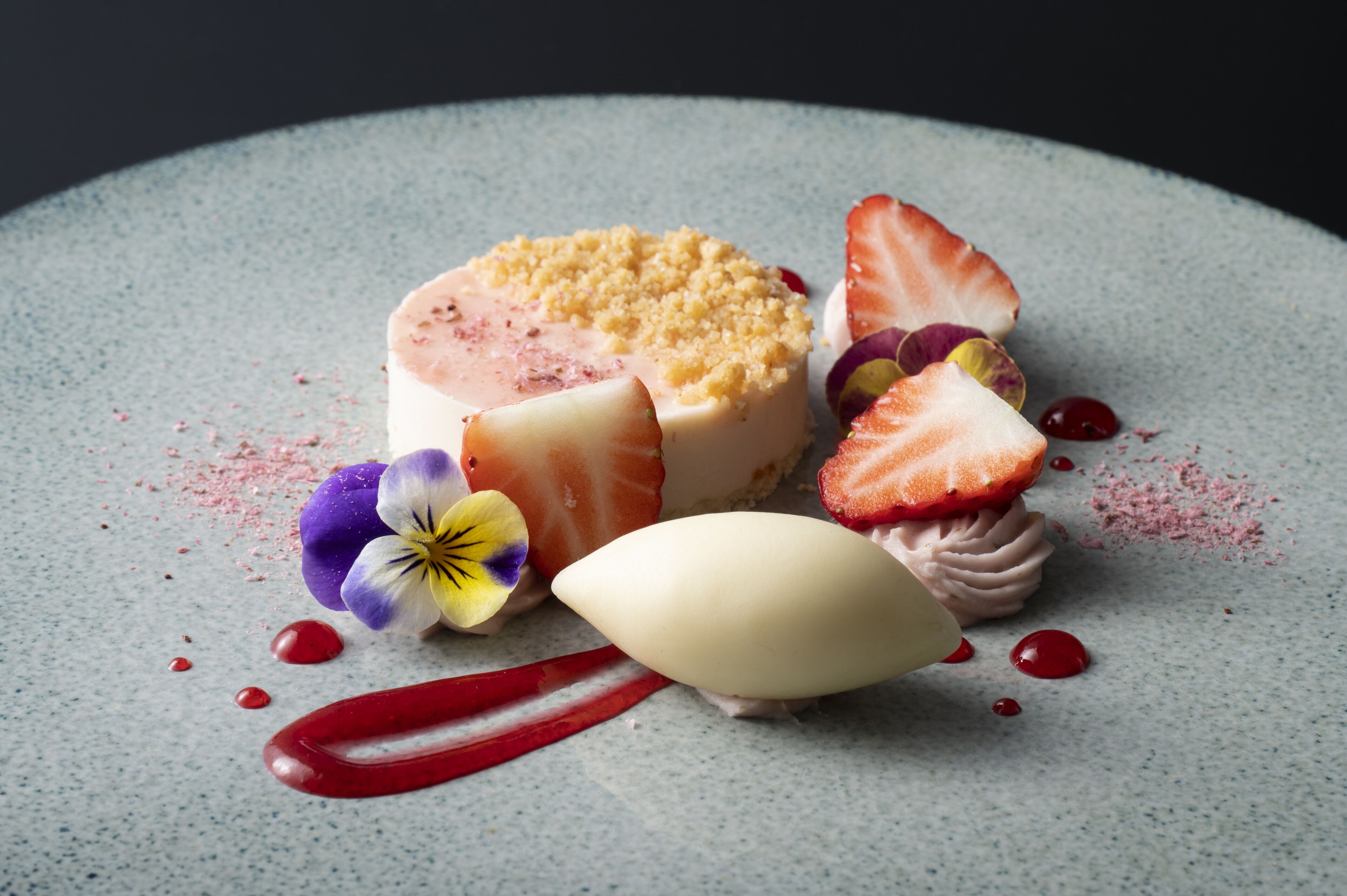 A dessert with strawberries, flowers, and a scoop of ice cream on a plate.