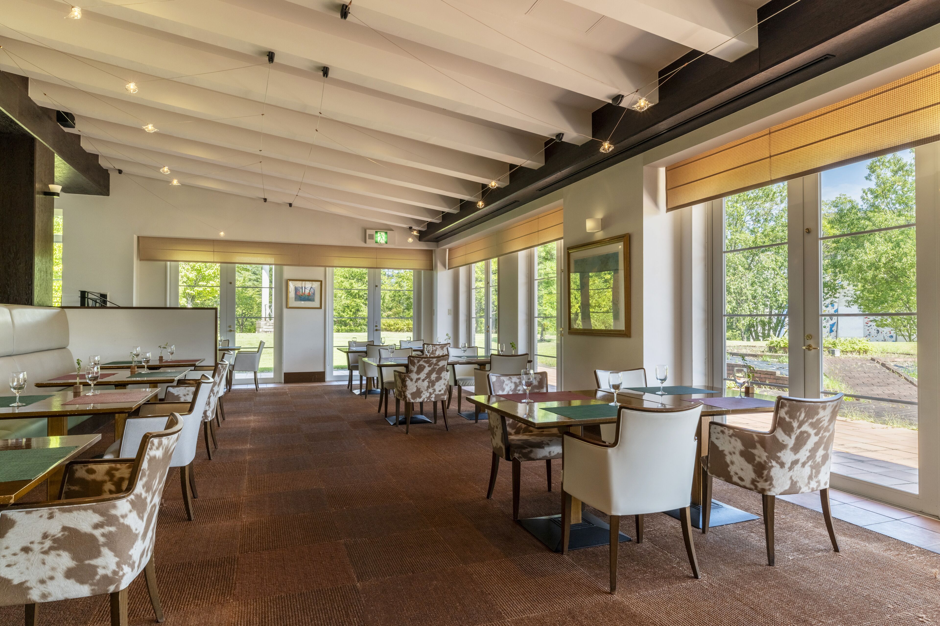 Ein geräumiges Restaurant mit hohen Decken, großen Fenstern und einer Mischung aus Tischen und Sitzbänken.