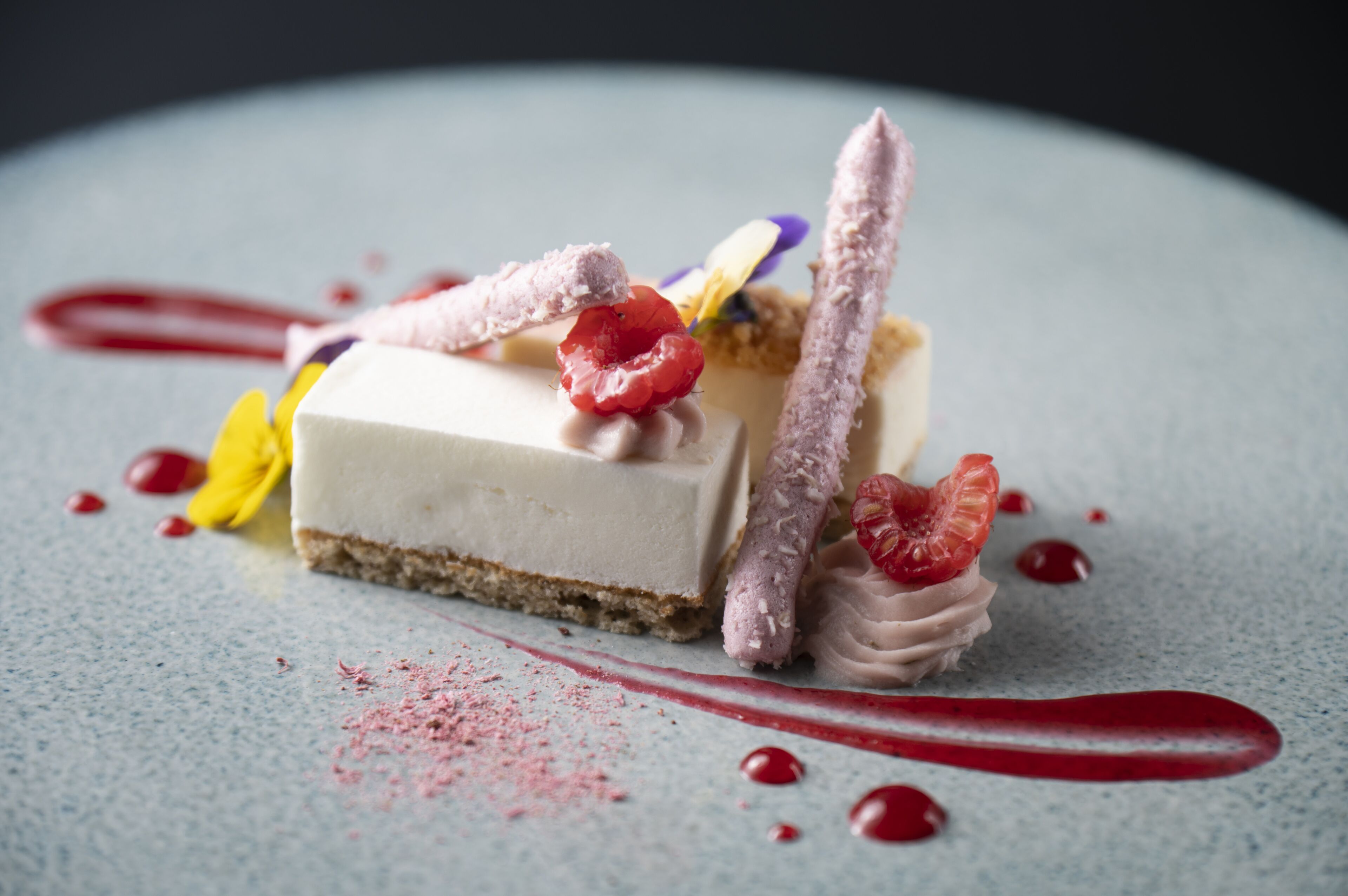 Un postre con base cremosa, coronado con diversas frutas y un adorno.