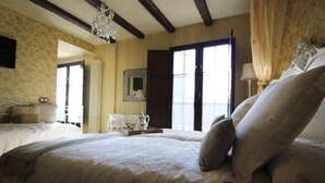 Een hotelkamer met een groot bed, een kroonluchter, een kaptafel en een raam met gordijnen.