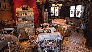 Een gezellig eetgedeelte met een tafel voor twee, omringd door antieke stoelen en een vloerkleed met een patroon.