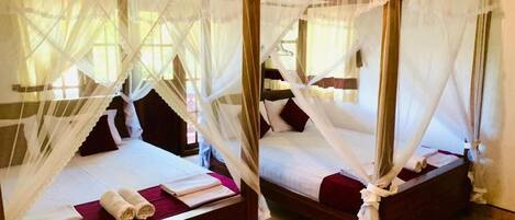 Two single beds with white canopies, each with a wooden frame and a red pillow.