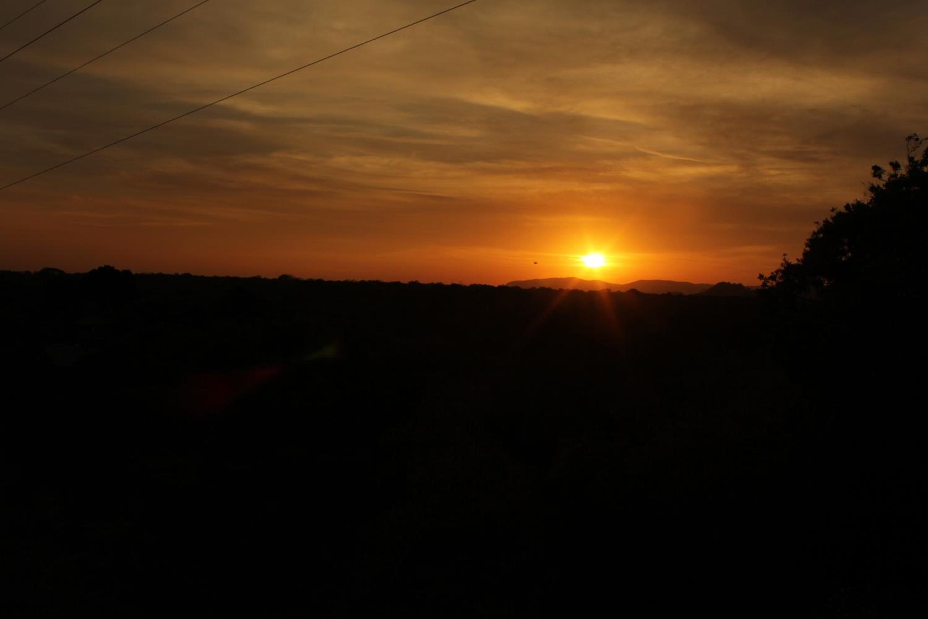 Un coucher de soleil, le soleil bas à l’horizon, projetant une lumière chaude sur le paysage.
