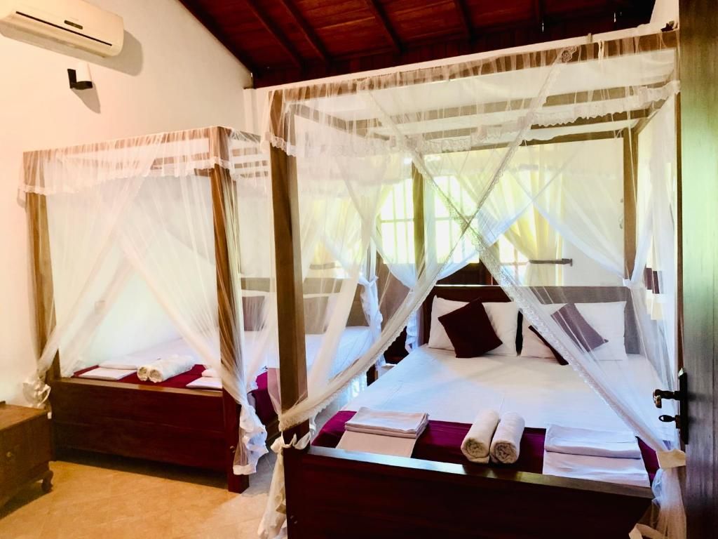 Two beds with canopy beds, a wooden headboard, and a bedside table with a lamp.