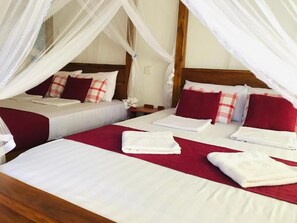 A hotel room with two beds, each with white linens and red accents, and a canopy bed with white linens. - Sinhagiri Villa (Sigiriya)