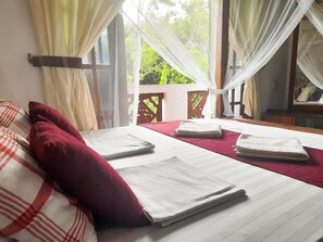 A hotel room with a bed, pillows, and a view of greenery outside. - Sinhagiri Villa (Sigiriya)