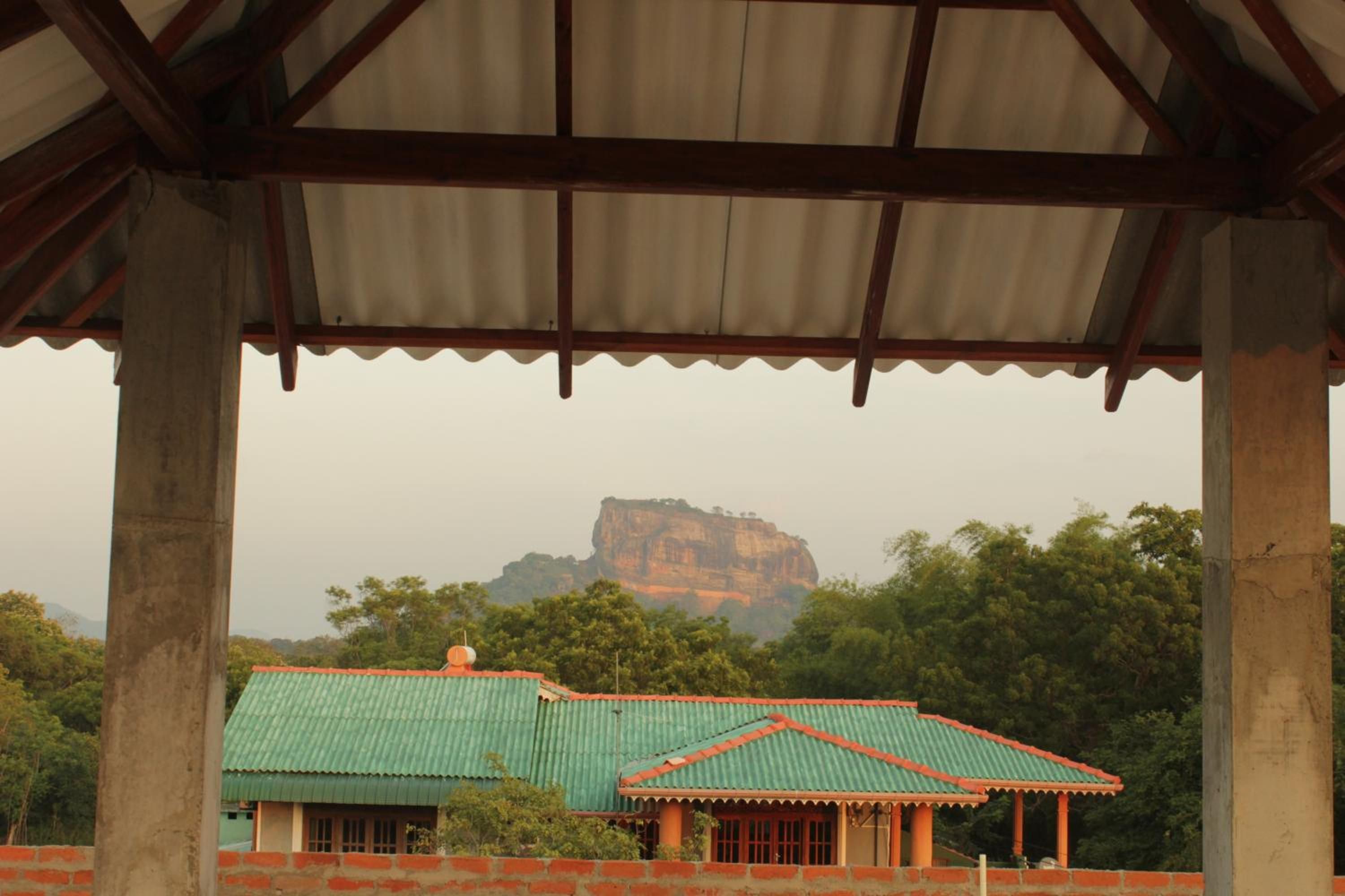 A building with a green roof and a large rock formation in the background.