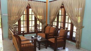 Una habitación con sofá, una mesa de centro y ventanas grandes con cortinas.