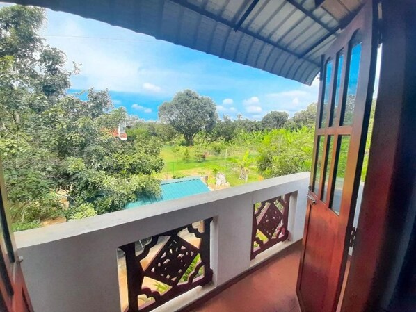 A balcony with a view of a lush garden and a swimming pool. - Sinhagiri Villa (Sigiriya)