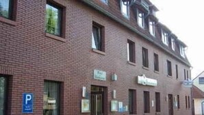 Een tweelaags bakstenen gebouw met een parkeersbord, ramen en een deur.