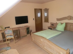 A bedroom with a bed, a desk, a chair, a television, and a wardrobe. - Glindenberger Hof (Wolmirstedt)