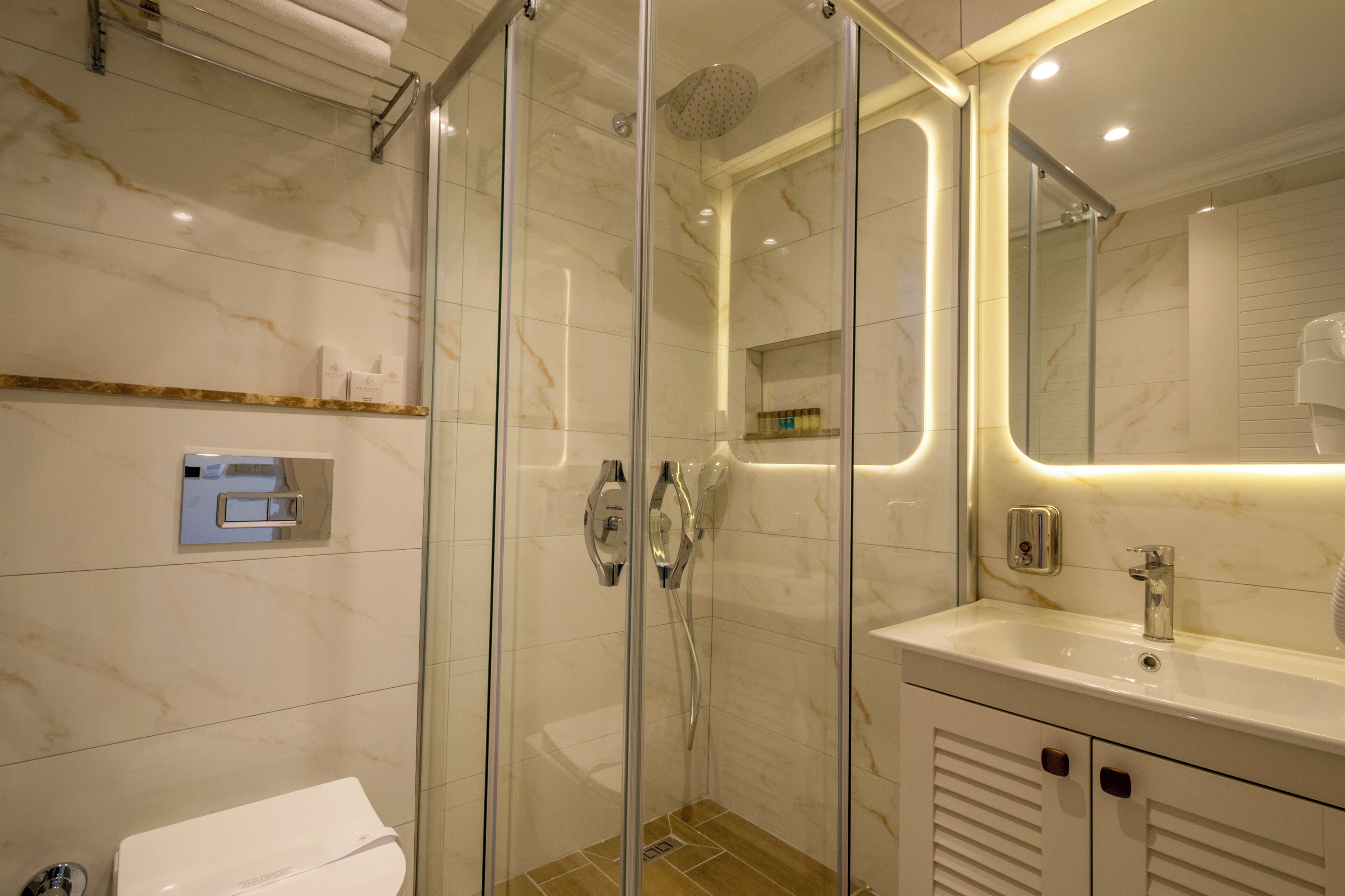 A modern bathroom with a glass-enclosed shower, a white sink with a mirror, and a toilet.