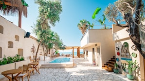 Ein Innenhof mit Pool, Sitzmöglichkeiten im Freien und einer Treppe, die zu einer oberen Ebene führt.