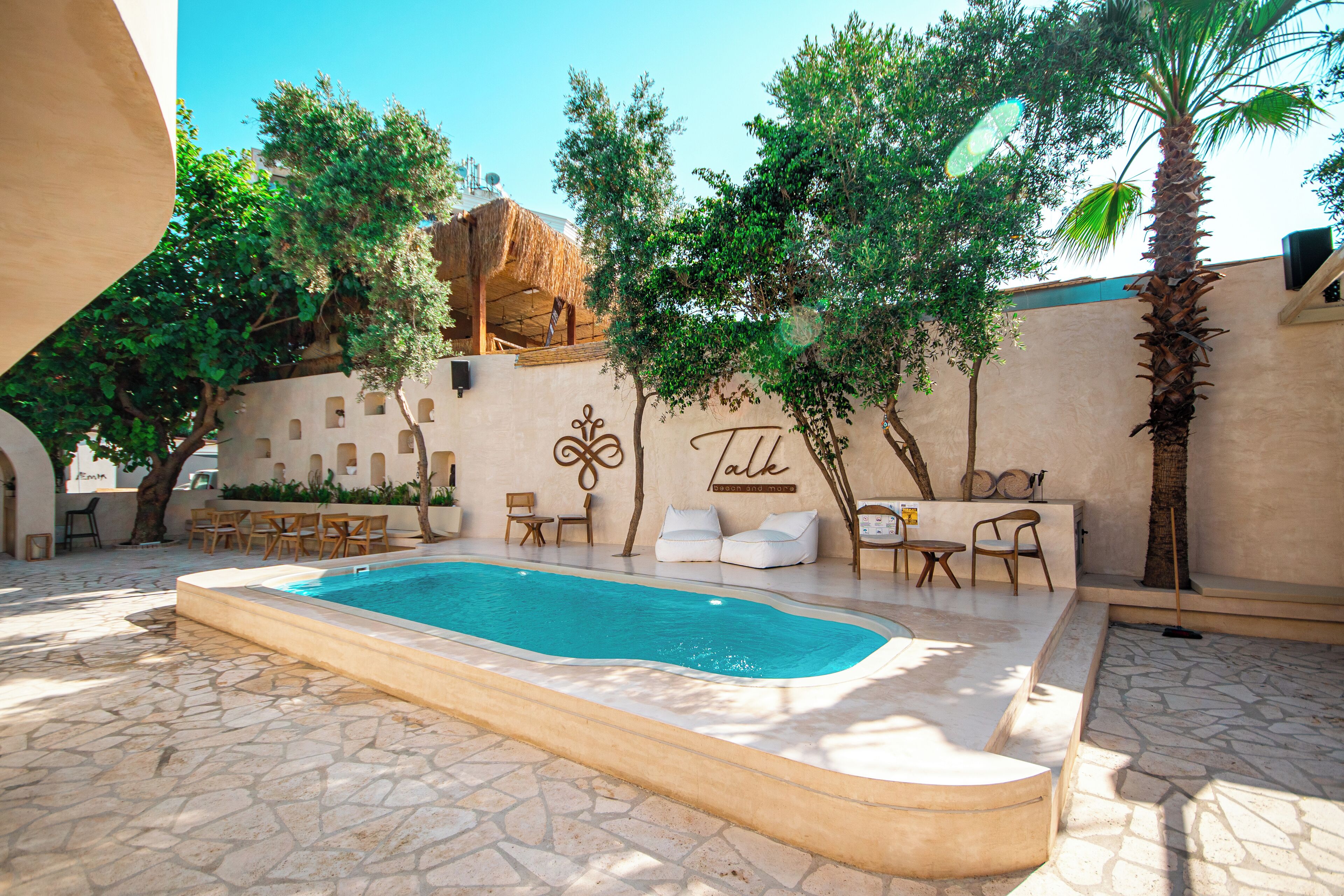 A swimming pool with a stone floor, surrounded by lounge chairs and a wall with a 'Talk' sign.