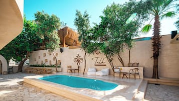 A swimming pool with a stone floor, surrounded by lounge chairs and a wall with a 'Talk' sign.