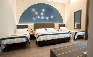 Ein Hotelzimmer mit drei Betten, einer großen, bogenförmigen Deckenleuchte und einem Spiegel an der Wand.