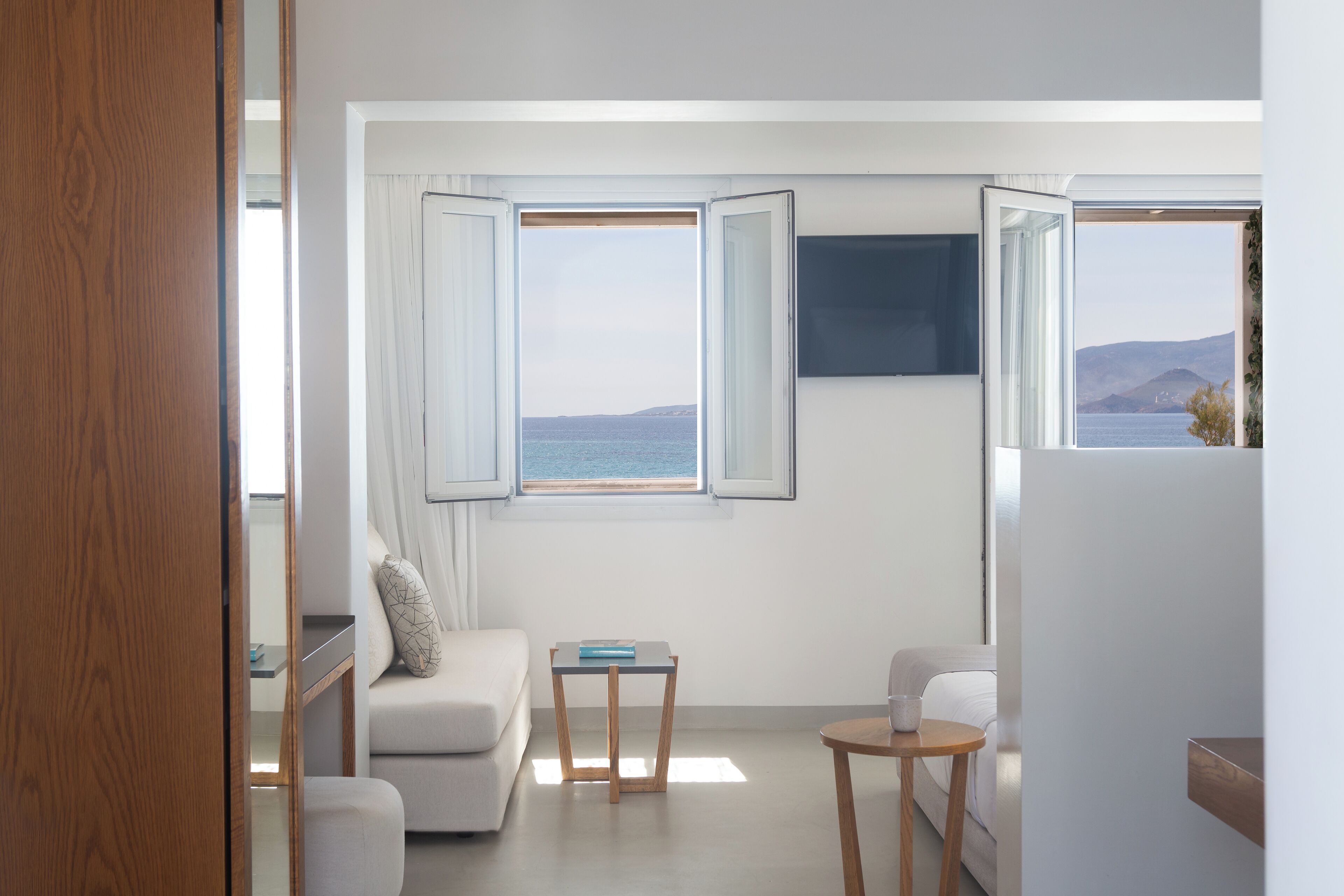 A modern room with a view of the sea, a sofa, a small table, and a chair.
