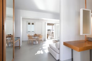A modern interior with a dining area, a sofa, and a wooden table.