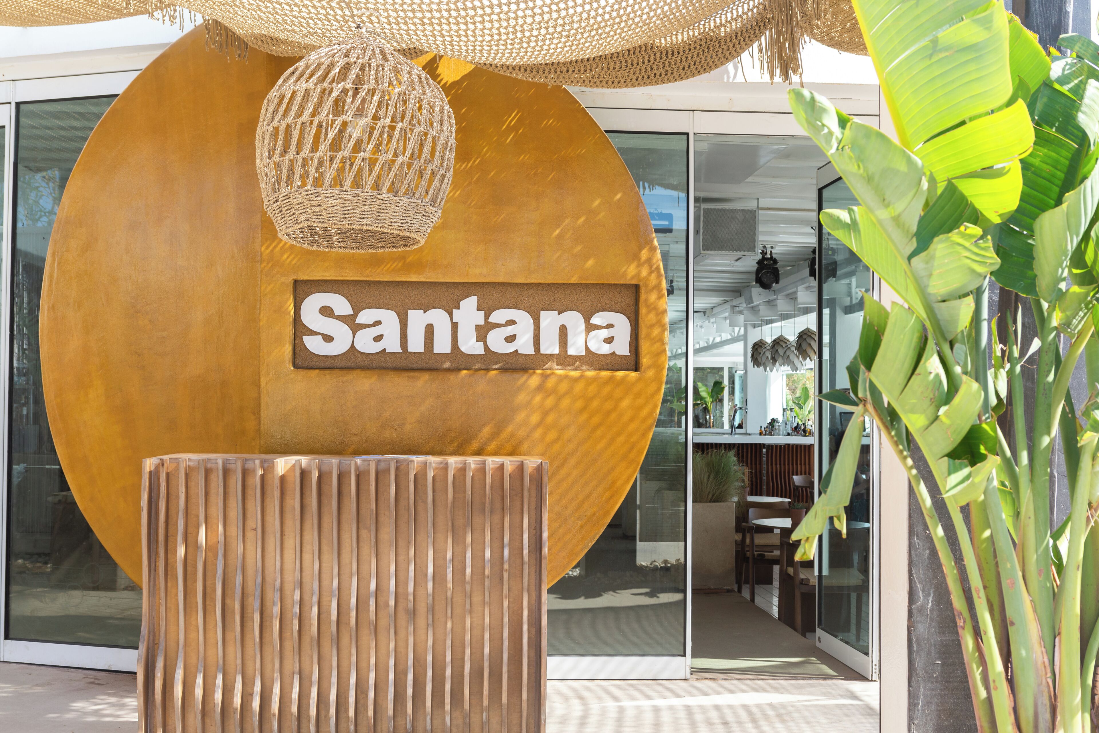 A large sign with the name 'Santana' in front of a modern building with glass doors.