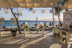 An outdoor dining area with tables, chairs, and sunflowers. - Santana Beach (Naxos)