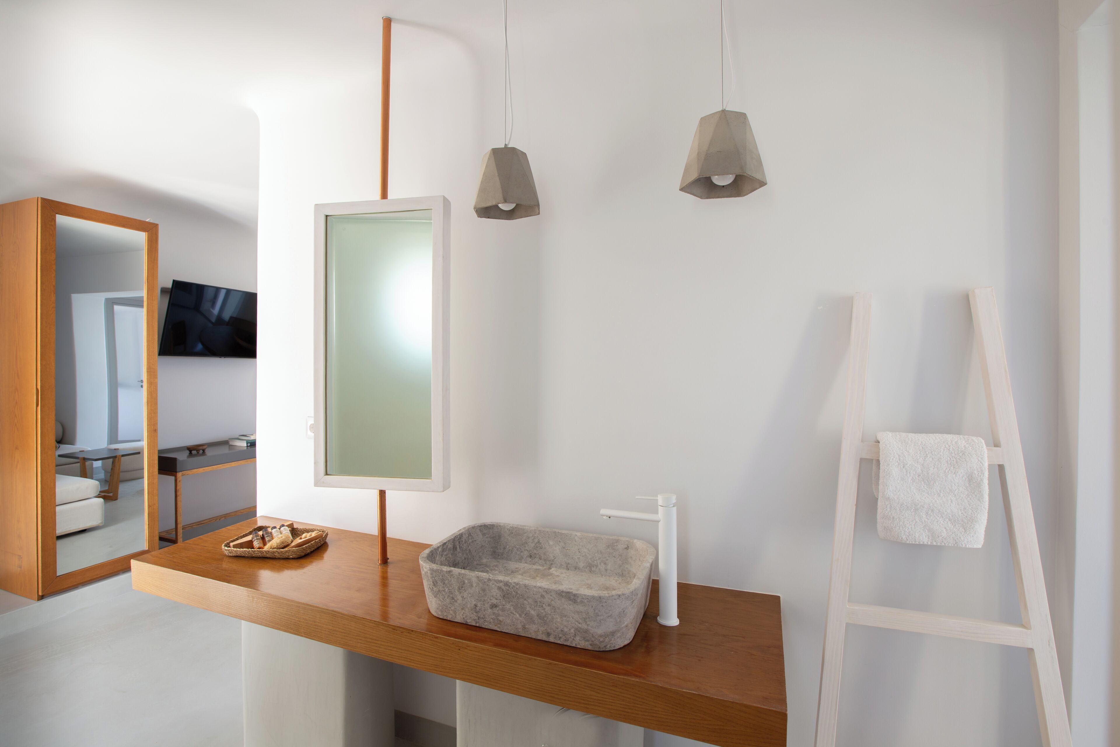 A modern bathroom with a wooden vanity, a stone basin, a mirror, and a towel rack.