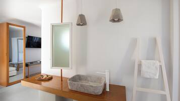 A modern bathroom with a wooden vanity, a stone basin, a mirror, and a towel rack.