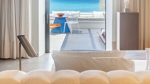 Une chambre d’hôtel moderne avec une grande fenêtre, un canapé, une petite table et une lampe.