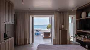 Une chambre d’hôtel avec un lit, une télévision, un bureau avec une chaise et une vue sur la mer.