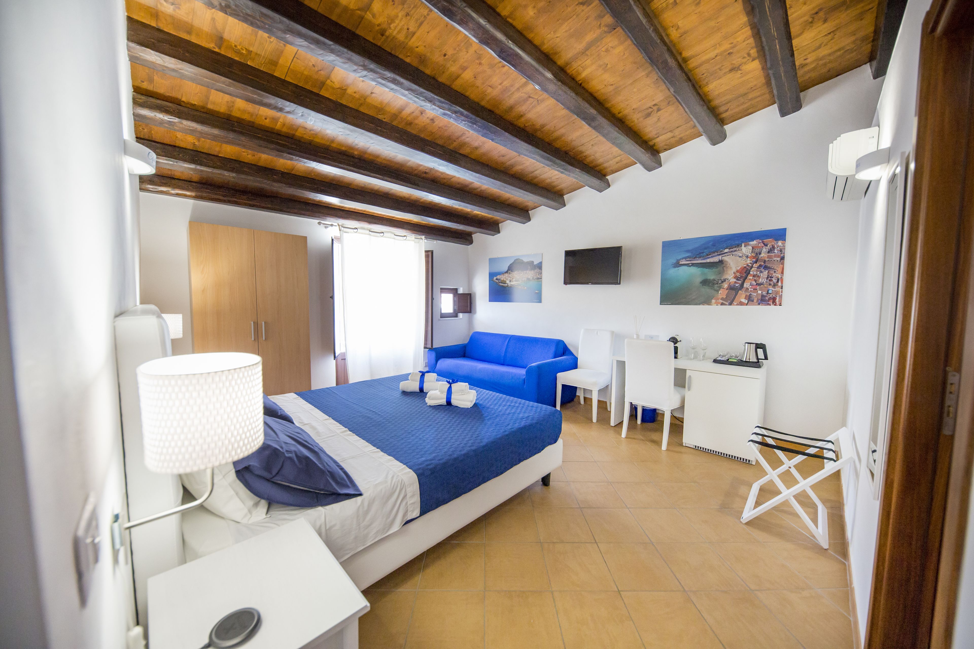 Ein Schlafzimmer mit Bett, Schreibtisch, Stuhl, Lampe und Fernseher.